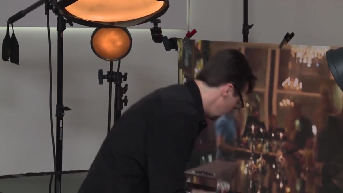 Photographer bracing arm while pouring whiskey into the glass