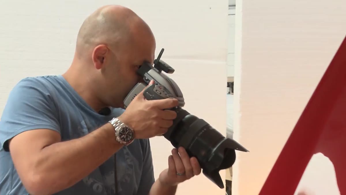 Photographer adjusting shutter speed settings on camera during car shoot