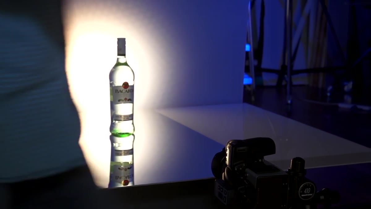 Silver card held near bottle neck bouncing light onto top of bottle