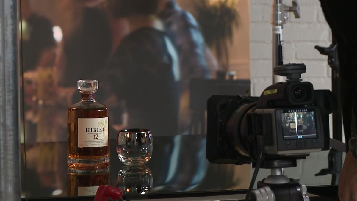 Photographer holding a reflector card by hand near the bottle